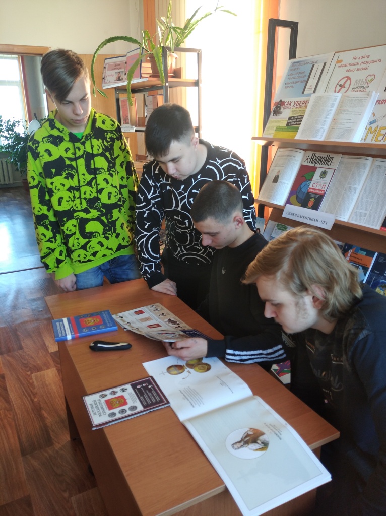 Юноши просматривают мультимедийные издания из фонда библиотеки